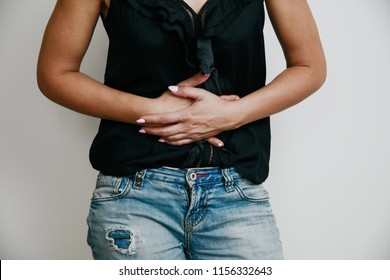 Abdominal Pain. Woman Suffers From Stomach Ache. Women's Problems, Menstruation, Indigestion. A Woman In A Black Blouse Is Holding Her Belly.