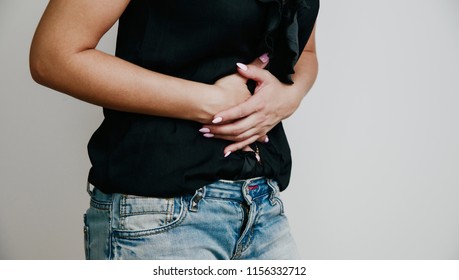 Abdominal Pain. Woman Suffers From Stomach Ache. Women's Problems, Menstruation, Indigestion. A Woman In A Black Blouse Is Holding Her Belly.