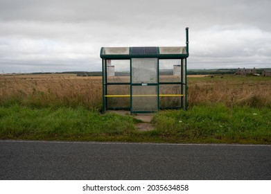 Aberdeenshire, Scotland, UK - August 29 2021: A Rural Bus Stop And Shelter With Fields And Farm In Background. Road In Foreground. No People.