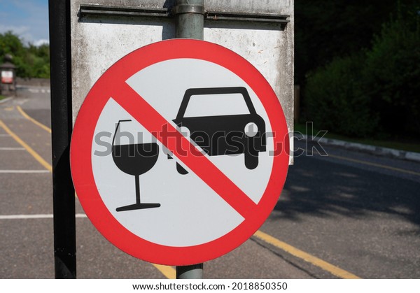 Aberlour, Scotland, UK - August 3 2021:\
Circular don\'t drink and drive sign with car and wine glass with\
red line through. Blurred background of road. Taken on road out of\
Aberlour Distillery.