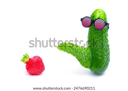 Abnormal cucumber with phallic growth and spiral-patterned sunglasses admires a hot and suggestive strawberry. Eye-catching aphrodisiacs, potency, and sexuality metaphorical concept.