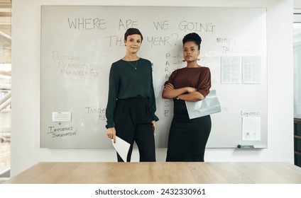 About to kill this presentation. Cropped portrait of two attractive young businesswomen standing in front of a whiteboard in their office boardroom.