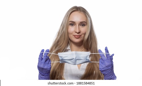 About To Put On Medical Face Mask Young Nurse With Long Straight Hair Looking At Camera. Caucasian Woman Wearing White Medical Uniform Isolated On White Background. 