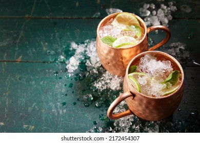 From Above Of Alcoholic Moscow Mule Beverages With Lime Slices And Ice Served In Copper Mugs On Shabby Wooden Table