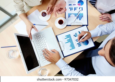 Above angle of human hands with business documents and laptop at meeting