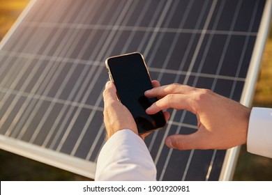 From above anonymous male analyzing data on mobile phone over photovoltaic panel during work on solar power station - Powered by Shutterstock