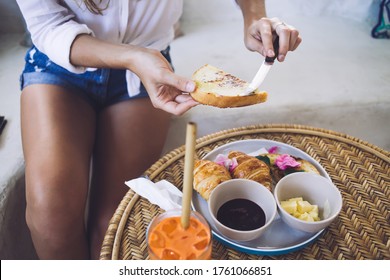 From Above Appetizing Croissant Orange Jam In Bowls Decorated With Flower And Crunchy Tasty Piece Of Bread In Hands Of Crop Tanned Stylish Woman Making Sandwich