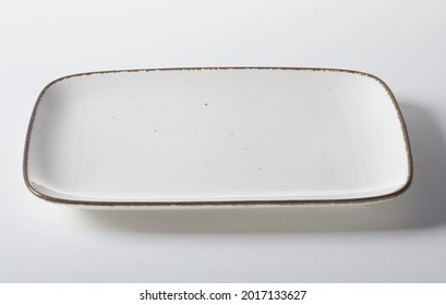 From above ceramic rectangle shaped plate with white enamel and black rim placed on gray background