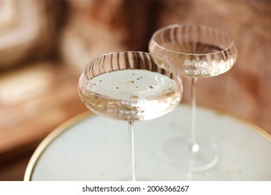 From Above Champagne From Bottle Into Glass Goblets On Round Table