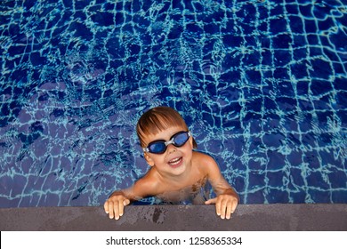 From Above Cheerful Funny Child In Goggles Swimming In Pool Near Edge And Looking At Camera