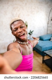 From Above Of Cheerful Young African American Transgender Woman With Dyed Hair In Pink Dress Smiling Brightly And Looking At Camera While Dancing And Showing Her Home