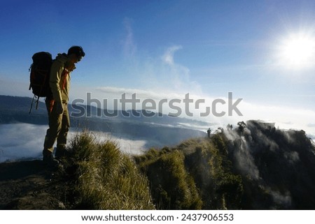 Above Cloud Nine, Mount Batur's Peak, Asian Man Trekker under Azure Sky and Cloud Sea