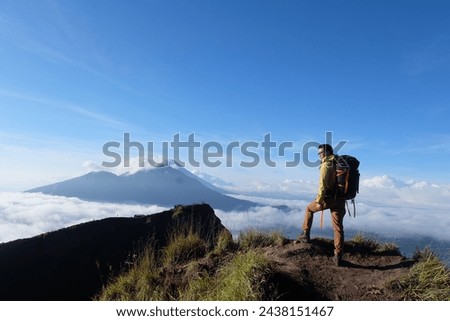 Above Cloud Nine, Mount Batur's Peak, Asian Man Trekker under Azure Sky and Cloud Sea