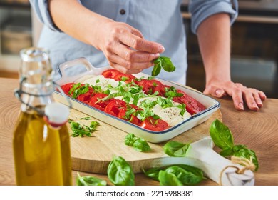 From Above Of Crop Anonymous Female In Casual Clothes Decorating Fresh Caprese With Basil In Ceramic Serving Dish Placed On Wooden Cutting Board Near Bottle Of Oil