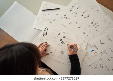 From above of crop anonymous female designer making sketches of various handmade jewellery accessories on paper sheets - Powered by Shutterstock