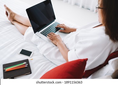 From Above Of Crop Anonymous Woman Resting On Bed In Hotel Room In Kuala Lumpur And Typing On Laptop Keyboard