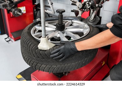 From above crop male worker of garage in gloves dismantling tire from rim using special machinery
