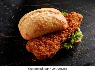 From Above Of Delicious German Sandwich With Crunchy Bun And Crispy Breaded Fried Cod Fish With Lettuce On Black Surface