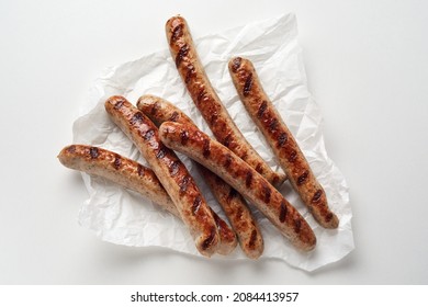 From Above Of Delicious Grilled Sausages Placed On Paper Napkin Against While Background In Studio