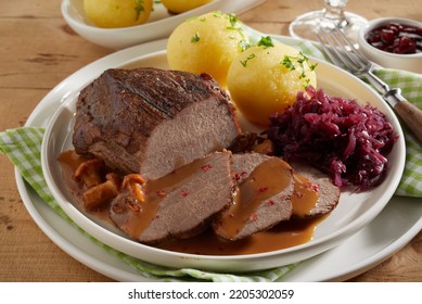 From Above Delicious Roasted Venison With Mushroom Sauce Served On Ceramic Plate Near Potato Dumplings And Red Cabbage Sauerkraut During Dinner