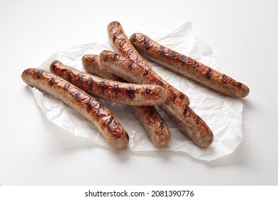 From Above Of Delicious Sausages Placed On Crumpled Paper Napkin Against White Background