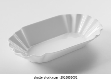 From Above Of Empty Clean Oval White Ceramic Serving Plate With Wavy Relief Design On White Background