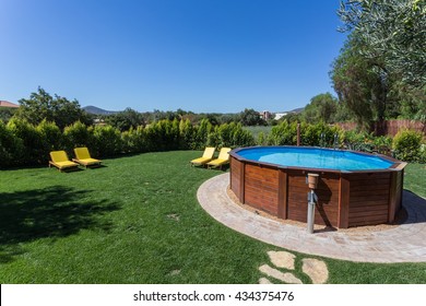 An Above Ground Pool Sets On A Concrete Pad In The Backyard On A Sunny Summer Day.