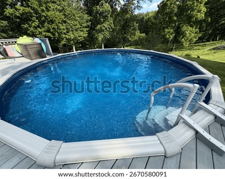 Above ground pool with steps and deck and trees in the background