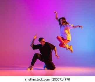 Above the ground. Two young people, guy and girl, dancing contemporary dance over pink background in neon light. Modern dance aesthetics concept