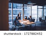 From above of group of diverse colleagues in formal clothing discussing business ideas while gathering at table in modern office and working together