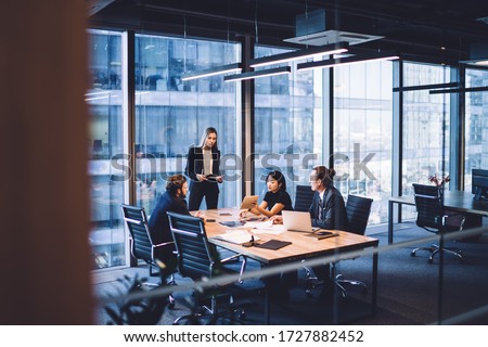 Photo of From above of group of diverse colleagues in formal clothing discussing business ideas while gathering at table in modern office and working together