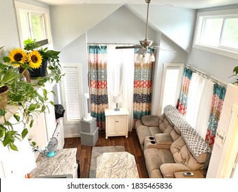From Above- Looking Down Onto A Living And Kitchen Area Of A Tiny House With Large Windows And Wood Floors With Lots Of Natural Sunlight.