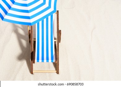 From Above Of Lounge Area On Beach With Striped Chair Under Umbrella.