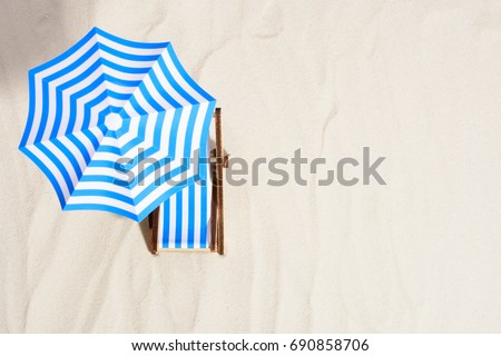 From above of lounge area on beach with striped chair under umbrella.