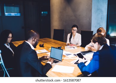 From Above Of Multiethnic Coworkers In Formal Wear Using Gadgets And Blank Screen Laptop While Waiting For Meeting At Stylish Conference Room 