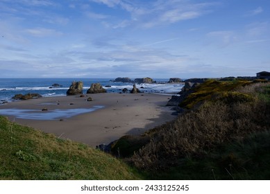 from above on a hill, a beautiful landscape photo of the pacific ocean with a sandy beach, large rock structures, blue sky with white wispy clouds on a sunny day on the coast - Powered by Shutterstock