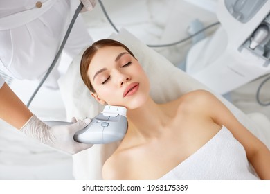 From Above Of Relaxed Young Female Client Getting SMAS Ultrasound Face Lifting Massage With Professional Equipment In Beauty Center