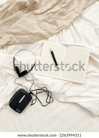 from above Retro Walkman with headphones and notebook with pen on a cozy bed in the morning on a sunny