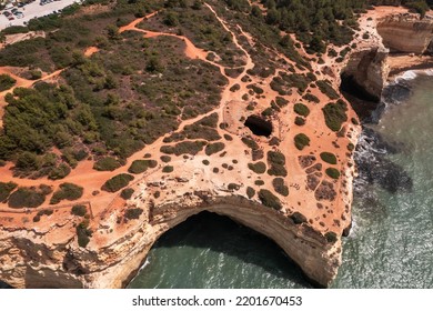 From Above Rough Cliff With Round Cave Located Near Sea Water On Sunny Day In Benagil, Portugal