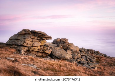 Above a sea of clouds on top of Mount Brocken in the Harz mountains, Harz National Park, Saxony-Anhalt, Germany. Pink sunset sky and rock formations in autumn. Brocken Teufelskanzel, Hexenaltar.