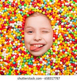From above shot of boy covered with sweets showing tongue out and winking at camera. 