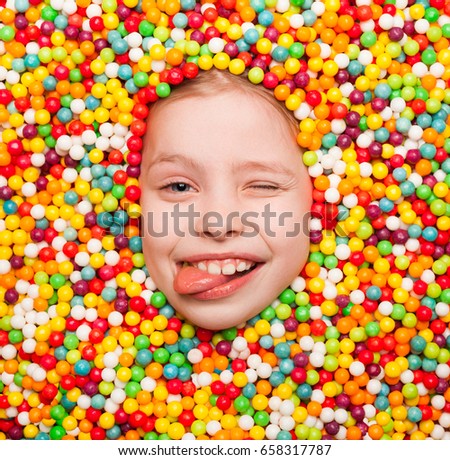 From above shot of boy covered with sweets showing tongue out and winking at camera. 