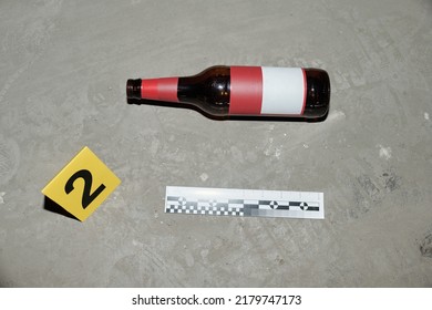 Above shot of empty beer bottle with blank sticker, yellow card with evidence number and ruler of crime scene investigator - Shutterstock ID 2179747173