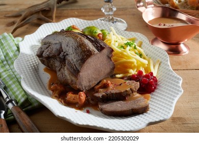 From Above Sliced Delicious Deer Venison Served With Cranberry Sauce On Plate Near Potato Fries And Brussels Sprouts On Wooden Table During Dinner