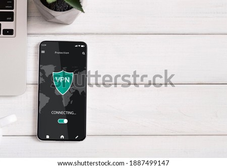 Above top high angle view of smartphone with vpn application on the sreen lying on the wooden table, free copy space for text or advert, flat lay. Information, location, cyber security