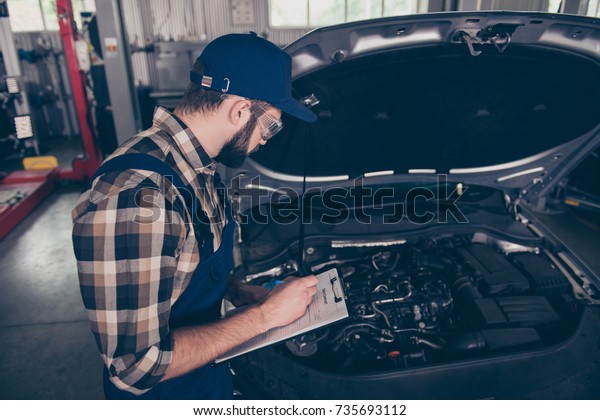 Above top view of focused, serious,\
concentrated expert professional engineer at mechanical work shop,\
in special safety outfit uniform, checkered shirt, hat head wear,\
filling the form of\
breakdown
