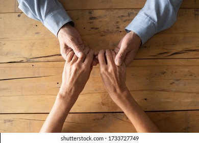 Above top view old senior man holding wrinkled hands of elderly wife, asking for apologize or giving psychological help. Loving senior mature family couple taking care of each other, support symbol.
