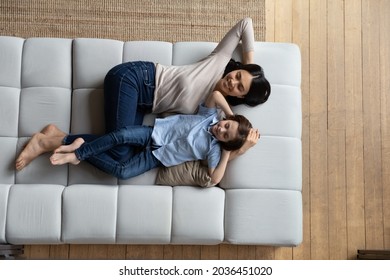 Above top view peaceful bonding millennial korean asian mother and happy small kid son sleeping together on comfortable couch. Relaxed multiracial diverse family daydreaming on weekend at home. - Powered by Shutterstock