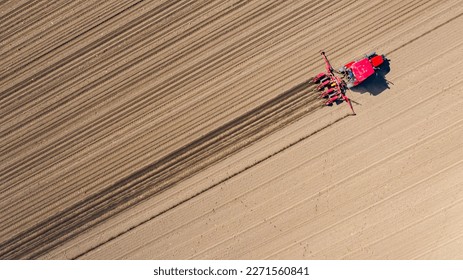 Above top view, of tractor as pulling mechanical seeder machine over arable field, soil, planting new cereal crop, corn, maize.