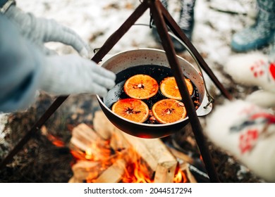 From above traditional mulled wine with slices of orange preparing in pot over burning logs in winter in countryside
